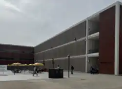 An image of Salazar Hall from the northeast side of the building, depicting students hanging out near the tables at the front.
