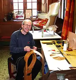 A seated, smiling craftsman