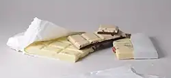Blocks of white chocolate piled on a table. Colored inclusions are visible.