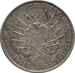 Weapons and standards crossed behind Swiss shield, wreath below. Legend and date along edge. Denomination at bottom.