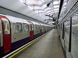 The interior of a building with a rounded ceiling and a white sign on the right wall reading "SEVEN SISTERS" in dark blue letters under a line
