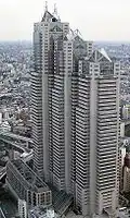 Aerial view of a beige high-rise lined with rows of windows; the building is composed of three adjoined towers of differing heights