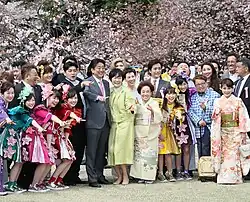 Shinzo Abe and Akie Abe standing in Shinjuku Gyoen under cherry blossom trees, pointing at the distance