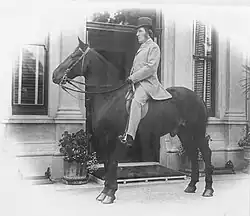 Black and white photograph of Hill riding his horse in front of Langford House.