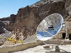 a parabolic mirror concentrates heat into a placeholder for kettles and pans.