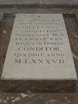 A stone slab on the ground with carved lettering on it