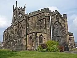 A low-angle shot of a stone church with the chancel foremost, and the tower in the background