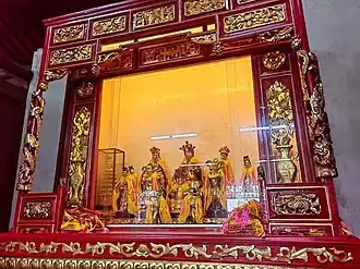 An elaborately decorated shrine housing statues of Guanyin and accompanying deities within the temple interior.