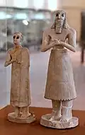 The god Abu (?) and a female statuette; 2800-2400 BC (Early Dynastic period); from the Square Temple of Abu at Tell Asmar (ancient Eshnunna (Iraq)); National Museum of Iraq. The loin-cloth has become recognizably a skirt and the twisted tufts have shrunk to a fringe[34]