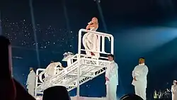 Swift standing on a bed onstage