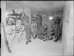British soldiers man machine guns inside a concrete bunker.