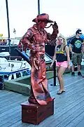 A woman performing as a living statue painted in bronze paint