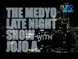 An image of buildings, with lights on. The show title is displayed on the left side of the image. The logo of GMA Network is displayed on the upper right side of the image.