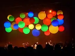 large colourful balloons suspended above a stage during a concert