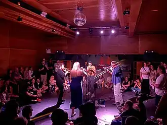 A brass quartet performs in a circle surrounded by audience members
