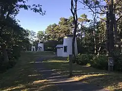 Photo showing the 3 Sisters lighthouses in their new position among the trees and down a winding path away from the coastline. There are 3 similar lighthouses with the beacon in the middle.