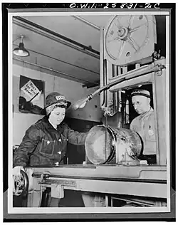 Band saw operator cutting metal pipe in a Todd Shipyards machine shop, circa 1943