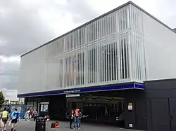 A white rectangular box of a building with a glazed screen bearing the National Rail and London Underground symbols and a blue band with the words "TOTTENHAM HALE STATION" above the wide entrance