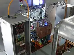 Two ion sources at the center with two high-voltage electronics cabinets next to them[38]