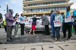 Two representatives bumping elbows as a sign of appreciation in front of donated boxes of vaccines