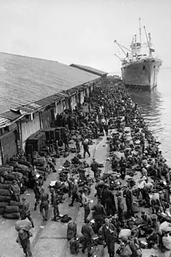 Troops unload supplies from a boat at a pier
