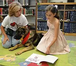 A 9-year-old student reading alongside a therapy dog. Those raised in the 2000s and 2010s are much less likely to read for pleasure than prior generations.