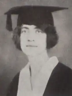 A young white woman with dark hair, wearing an academic cap and gown