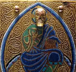 Detail from 13th century Limoges chasse, with a projecting modelled head on a flat background.