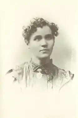 Portrait photograph of Voltairine de Cleyre, wearing a dress and short curly hair