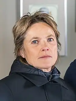 close-up image of Karoline Eichhorn wearing a black coat, with a padded winter jacket visible underneath, looking intently at camera
