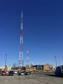 A two-story studio building, with WIVB "We're 4 Buffalo" signage, on a property with two orange-and-white towers, one tall and one short.