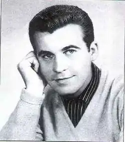 1950s-styled portrait of young caucasian male with dark hair wearing a dark striped shirt and light sweater