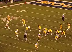 American football players line up for a play in a full stadium.