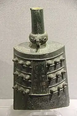 Bell with three rows of three knobs on each side, swirling decorative patterns and an inscription