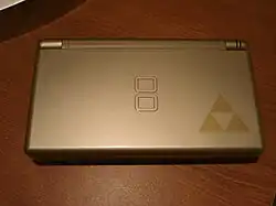 A gray handheld video game device with the Triforce logo in the bottom-right corner, which looks like three triangles touching at their points.