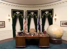 The Hoover desk with a large globe next to it in a recreation Oval Office.
