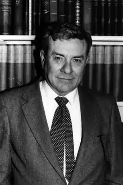 Larry Dean Benson pictured standing in front bookshelves at Harvard, ca. 1980.